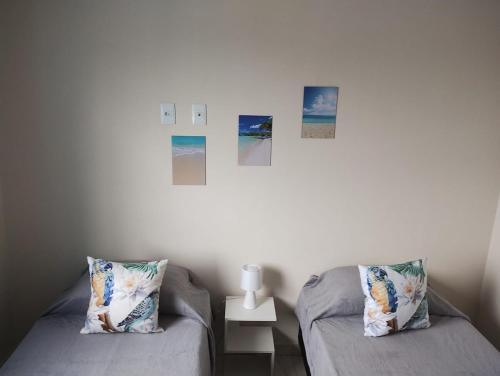 - 2 lits dans une chambre avec des photos sur le mur dans l'établissement Apartamento Praia do Sonho- CasaMora, à Palhoça