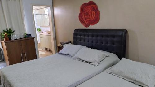 a bedroom with a bed with a red rose on the wall at Casa e Ateliê de pintura Neiva Mario in São Gabriel
