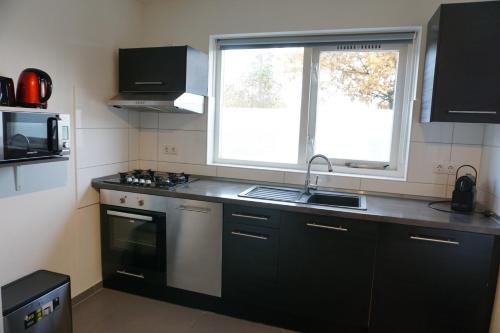 a kitchen with a sink and a stove and a window at Kustverhuur, Vakantiepark Fort Soleil 36 in Breskens