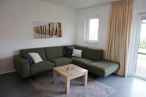 a living room with a green couch and a coffee table at Kustverhuur, Vakantiepark Fort Soleil 36 in Breskens