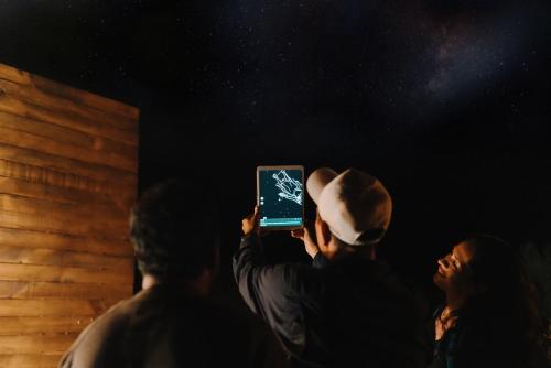 a man is taking a picture with a cell phone at Wander Cabins, Cabaña con Vista Única a la Sierra de Artega in Arteaga