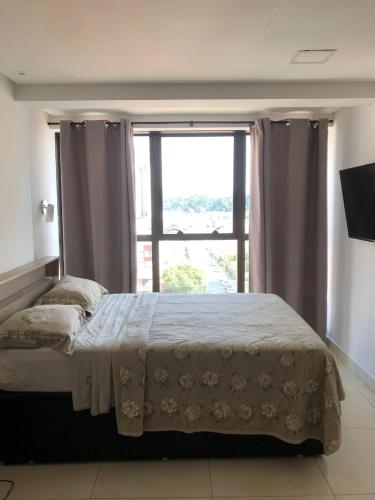 a bedroom with a bed with a large window at Gold flat Manaíra 602 in João Pessoa