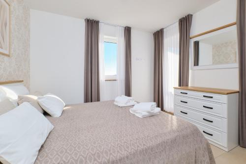 a bedroom with a bed with white pillows and a dresser at Apartments Divna in Mali Lošinj