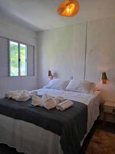 a bedroom with a large bed with towels on it at Aquavit pousada e comedoria in Jacumã