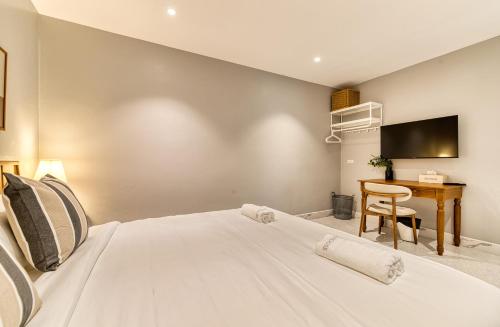 a bedroom with a white bed and a desk at AB House in Bangkok