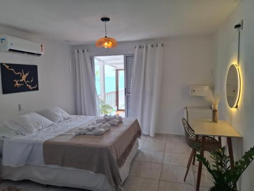 a bedroom with a bed and a table and a window at Aquavit pousada e comedoria in Jacumã