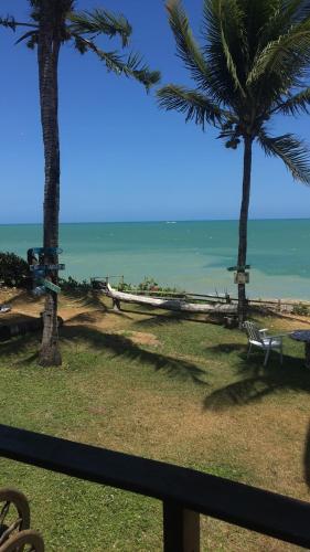 a view of a beach with palm trees and the ocean at Aquavit pousada e comedoria in Jacumã