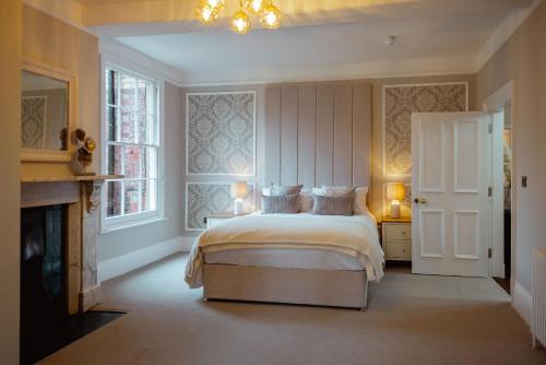 a white bedroom with a bed and a fireplace at The Manor Lodge, Repton in Repton
