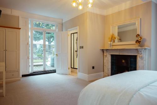 a bedroom with a fireplace and a bed and a mirror at The Manor Lodge, Repton - Luxury Derbyshire Home Sleeps 14 in Repton