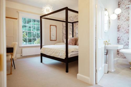 a bedroom with a canopy bed and a sink at The Manor Lodge, Repton - Luxury Derbyshire Home Sleeps 14 in Repton