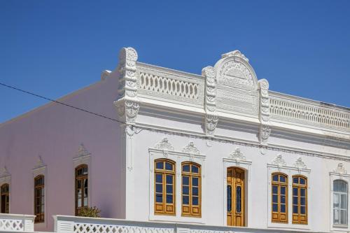 a white building with orange doors and a balcony at Casa de Marim AL in Olhão