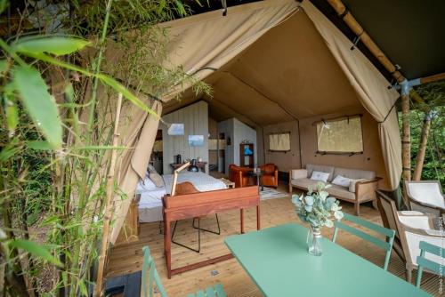 a room in a tent with a bed and a table at Hôtel Diana Dea Lodge & SPA in Sainte-Anne-les Hauts