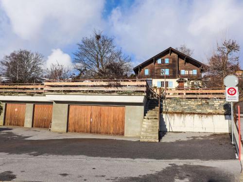 a building with two garage doors and a house at Chalet Sergnoud by Interhome in Lens