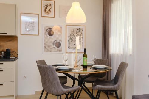 a dining room with a table with chairs and a bottle of wine at Apartments Divna in Mali Lošinj