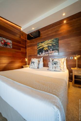a bedroom with a large bed with wooden walls at Hôtel Diana Dea Lodge & SPA in Sainte-Anne-les Hauts