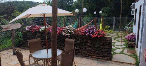 a table and chairs and an umbrella and some flowers at Pousada Aconchego in Pirenópolis