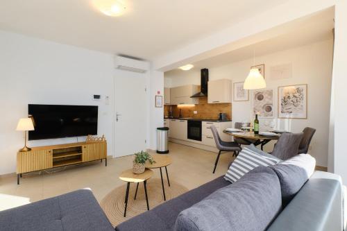 a living room with a blue couch and a kitchen at Apartments Divna in Mali Lošinj