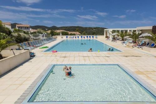 un groupe de personnes dans une grande piscine dans l'établissement Charmante Villa 4 pers piscine terrasse 600 m de la plage, à Belgodère