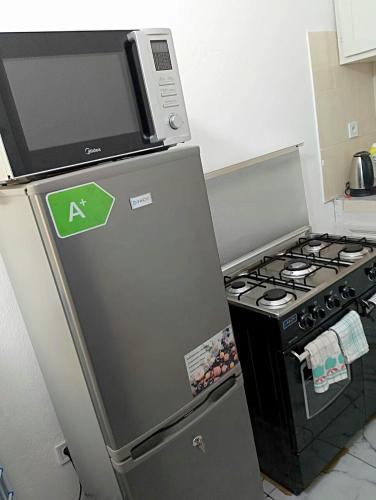 a kitchen with a stove and a microwave on top of a refrigerator at Residence le prestige in Kribi