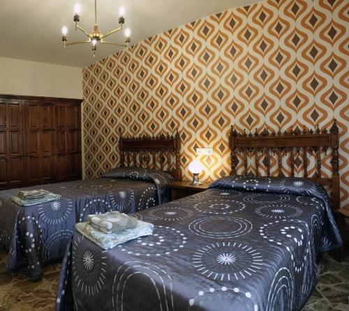 a bedroom with two beds and a patterned wall at Casa tio peguero - piscina spa in San Bartolomé de Pinares