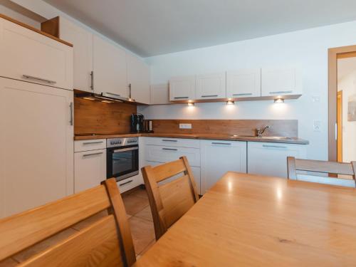 a kitchen with white cabinets and a wooden table at Apartment Talmoosen-Bauer by Interhome in Dorf