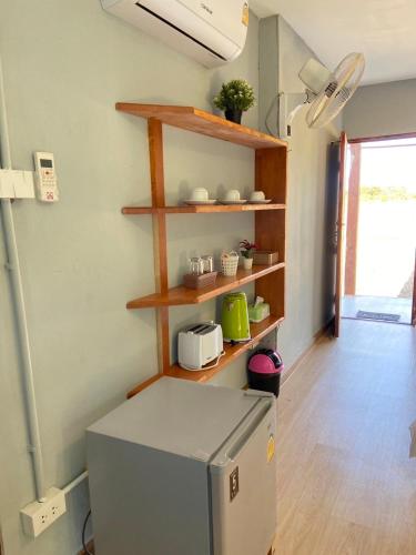 a kitchen with a refrigerator and wooden shelves at ID Garden Home in Ban Cham Kha