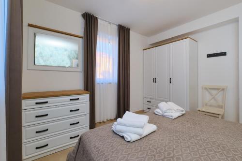 a bedroom with a bed and a dresser with white towels at Apartments Divna in Mali Lošinj