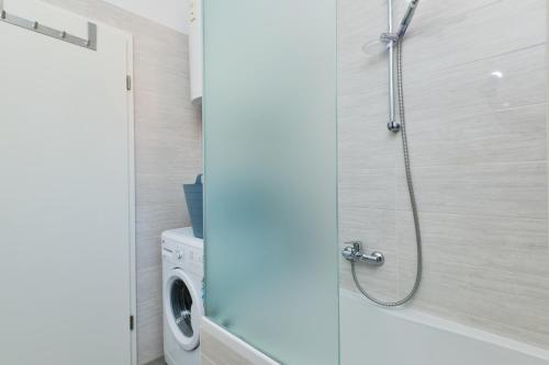 a shower in a bathroom with a washing machine at Apartments Divna in Mali Lošinj