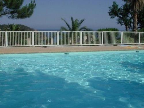 une piscine d'eau bleue en face d'une clôture dans l'établissement Appartement T2 vue mer à 600 m de la plage du Canadel, à Rayol-Canadel-sur-Mer