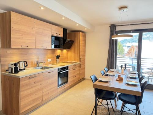 une cuisine avec des armoires en bois et une table avec des chaises dans l'établissement Appartement moderne aux Gets avec parking et WIFI proche centre - FR-1-623-133, aux Gets