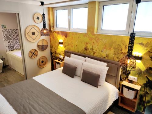 a bedroom with a bed with white sheets and windows at Studios Design by Les Béthunoises in Béthune