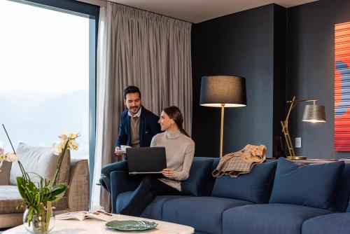 a man and a woman sitting on a couch with a laptop at Hilton Bogota Corferias in Bogotá