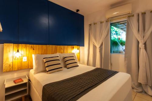 a bedroom with a large bed with blue walls and a window at Pituba Ville - Ap 1 - 2 Quartos in Itacaré