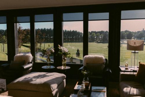 a living room with a view of a field through windows at Haras Santa María del Mar in Mar del Plata
