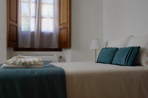 a bedroom with a bed with blue pillows and a window at Casa de Marim AL in Olhão