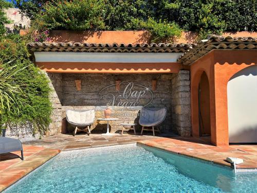 - une piscine avec des chaises et une table à côté d'un mur dans l'établissement Magnifique Villa classée 4 étoiles avec piscine et vue mer à Cavalière, au Lavandou
