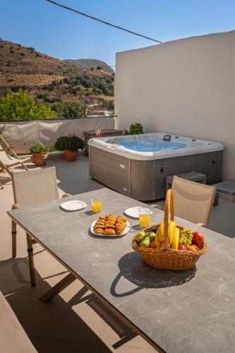 a table with a bowl of fruit and a basket of bread at Casa Kastella, private jacuzzi & BBQ facilities! in Angouselianá