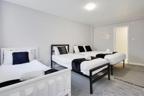 three beds in a room with white and black at Azure Beach Hotel in Bournemouth