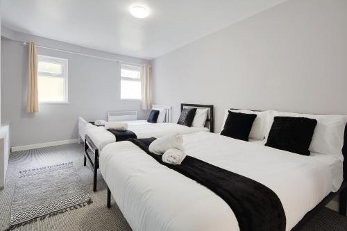 three beds in a room with white and black at Azure Beach Hotel in Bournemouth
