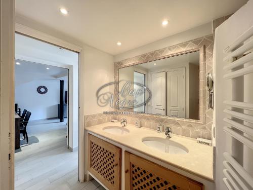 Un baño con dos lavabos y un espejo grande. en Appartement plain-pied avec terrasse proche de la plage du Canadel, en Rayol-Canadel-sur-Mer