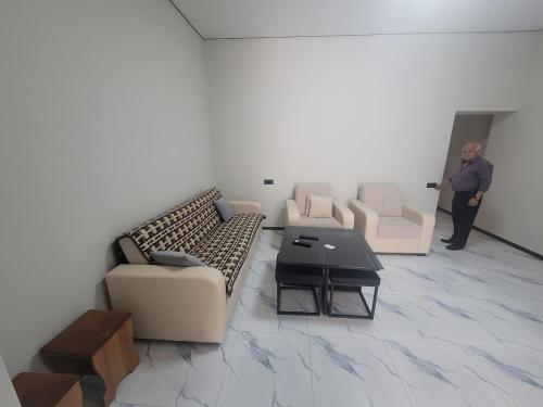 a man standing in a room with couches and a table at Tsaghkadzor Inn Guest House in Tsaghkadzor