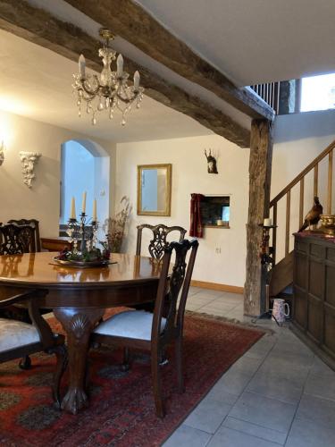 une salle à manger avec une table en bois et un lustre dans l'établissement La Goulaiserie, à Gathemo