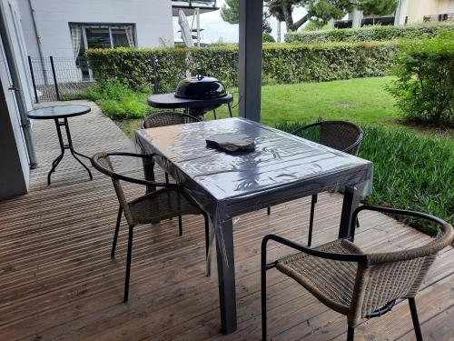 une table et des chaises sur une terrasse avec un chapeau dans l'établissement Appartement 67 m2 avec 100 m2 jardin privatif RESERVABLE UNIQUEMENT PAR PERIODE DE 7 JOURS MINIMUM DU SAMEDI AU SAMEDI, à Arcachon