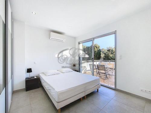 une chambre blanche avec un lit et un balcon dans l'établissement Maison moderne pour 4 personnes proche de la plage de Cavalière - Le Lavandou, au Lavandou