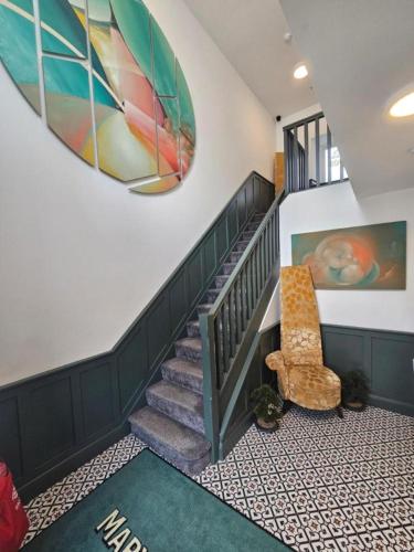 a hallway with a staircase with a chair and a painting at Mary Mullen's Rooms Eyre Square. in Galway
