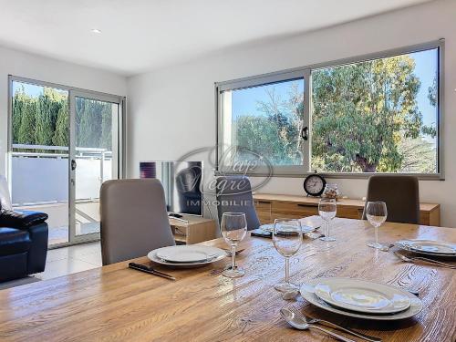 une salle à manger avec une table, des chaises et des fenêtres dans l'établissement Maison moderne pour 4 personnes proche de la plage de Cavalière - Le Lavandou, au Lavandou