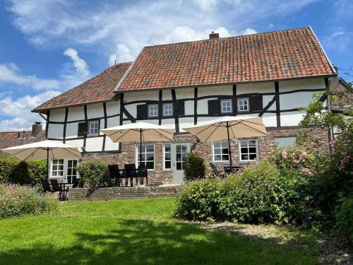 a large house with umbrellas in front of it at Vakantiewoningen 'Hoeve de Witte Olifant' in Noorbeek