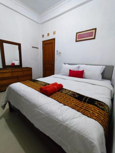 a bedroom with a large bed with red pillows on it at Kadipiro Homestay in Ngabean
