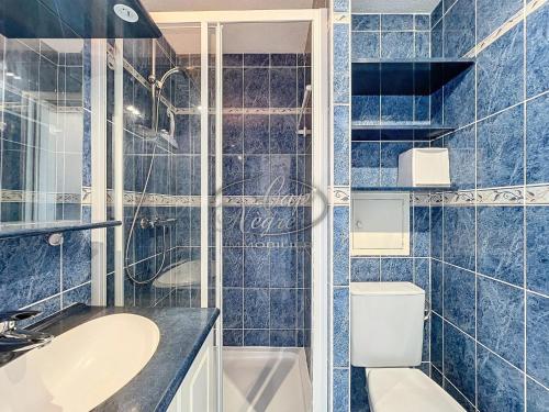 La salle de bains est pourvue de carrelage bleu, d'un lavabo et de toilettes. dans l'établissement Appartement pour 4 personnes à 50 m de la plage, au Lavandou