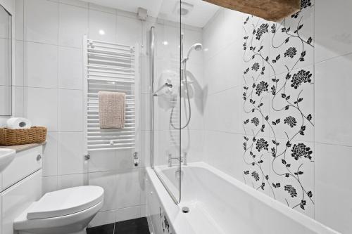 a white bathroom with a toilet and a shower at Primrose Cottage in Matlock